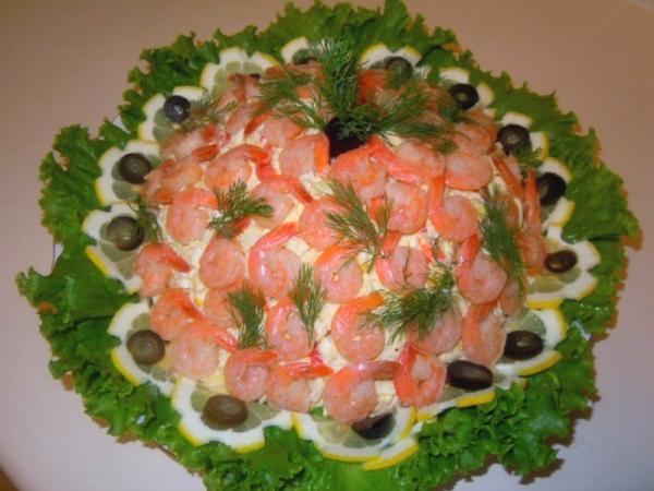 салат на блюде украшенный креветками  листьями салата и маслинами